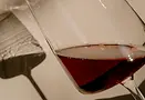 A close up of a glass of red wine with the shadow of the glass in the background