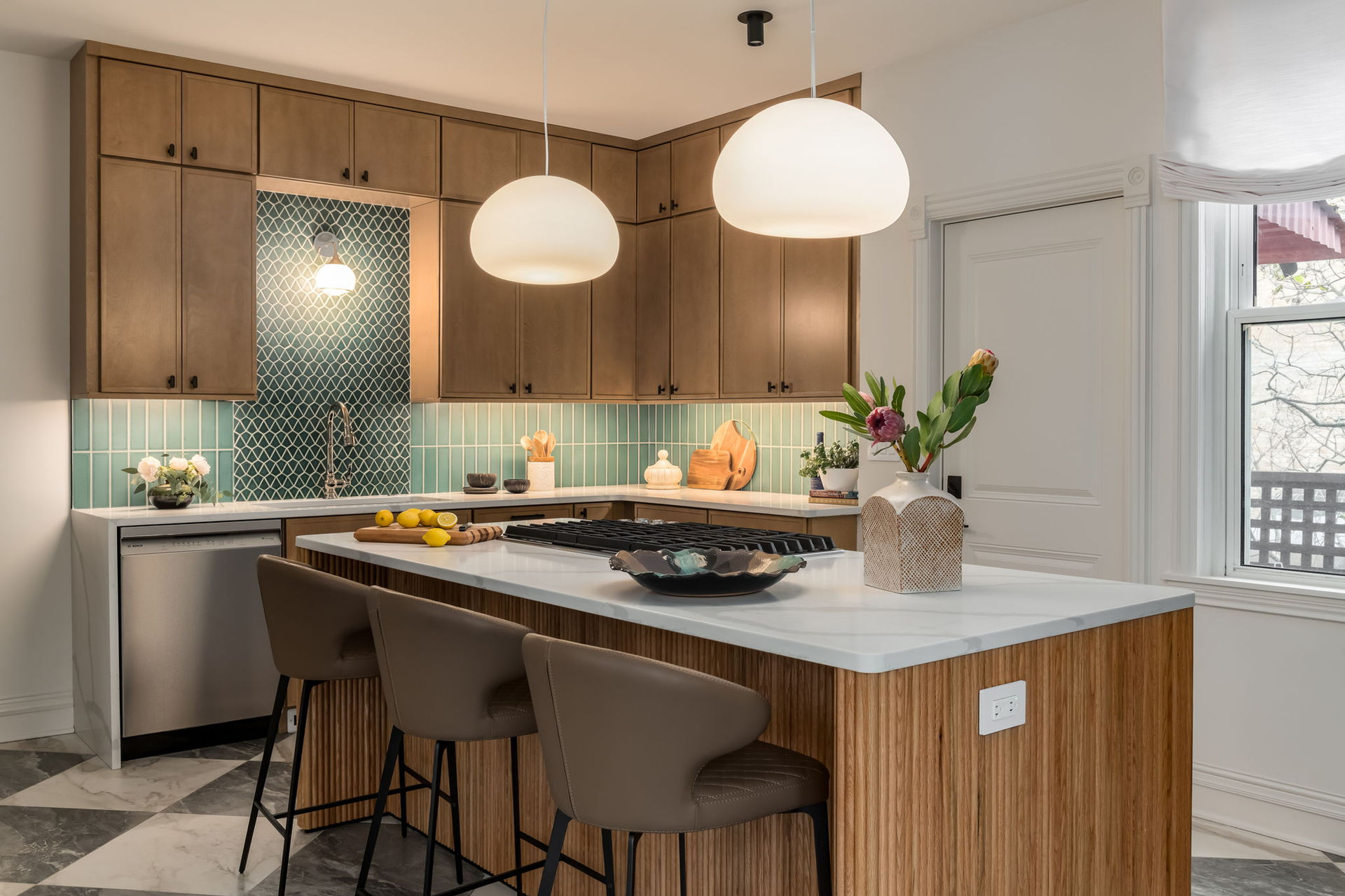 Warm modern kitchen lighting with green backsplash and marble checkerboard floor.