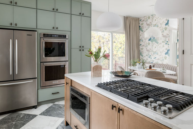 Tambour island with gas downdraft cooktop, built in microwave drawer, green pantry cabinets, and marble checkerboard kitchen flooring.