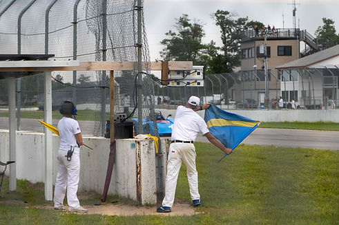 Two workers on station, one blue flagging an SRF car. Photo by Megan Woodson Photography