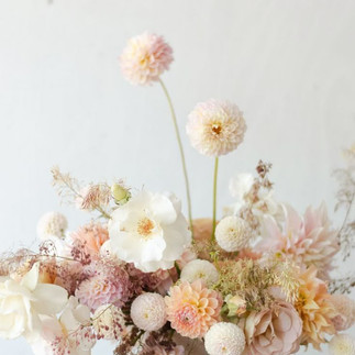 Composition florale de mariage aux teintes blush et pastel avec dahlias, roses et fleurs texturées séchées, parfaite pour une décoration de mariage poétique en 2026