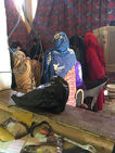 Women in blue and red head coverings sitting indoors