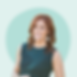 Smiling woman with red hair and green dress, light blue background photo.