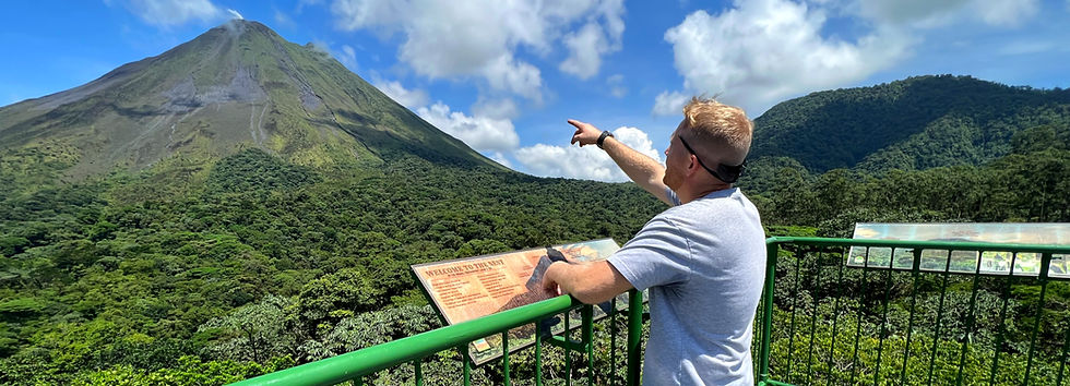 A man points to Arenal Volcano from atop scaffolding in Costa Rica.