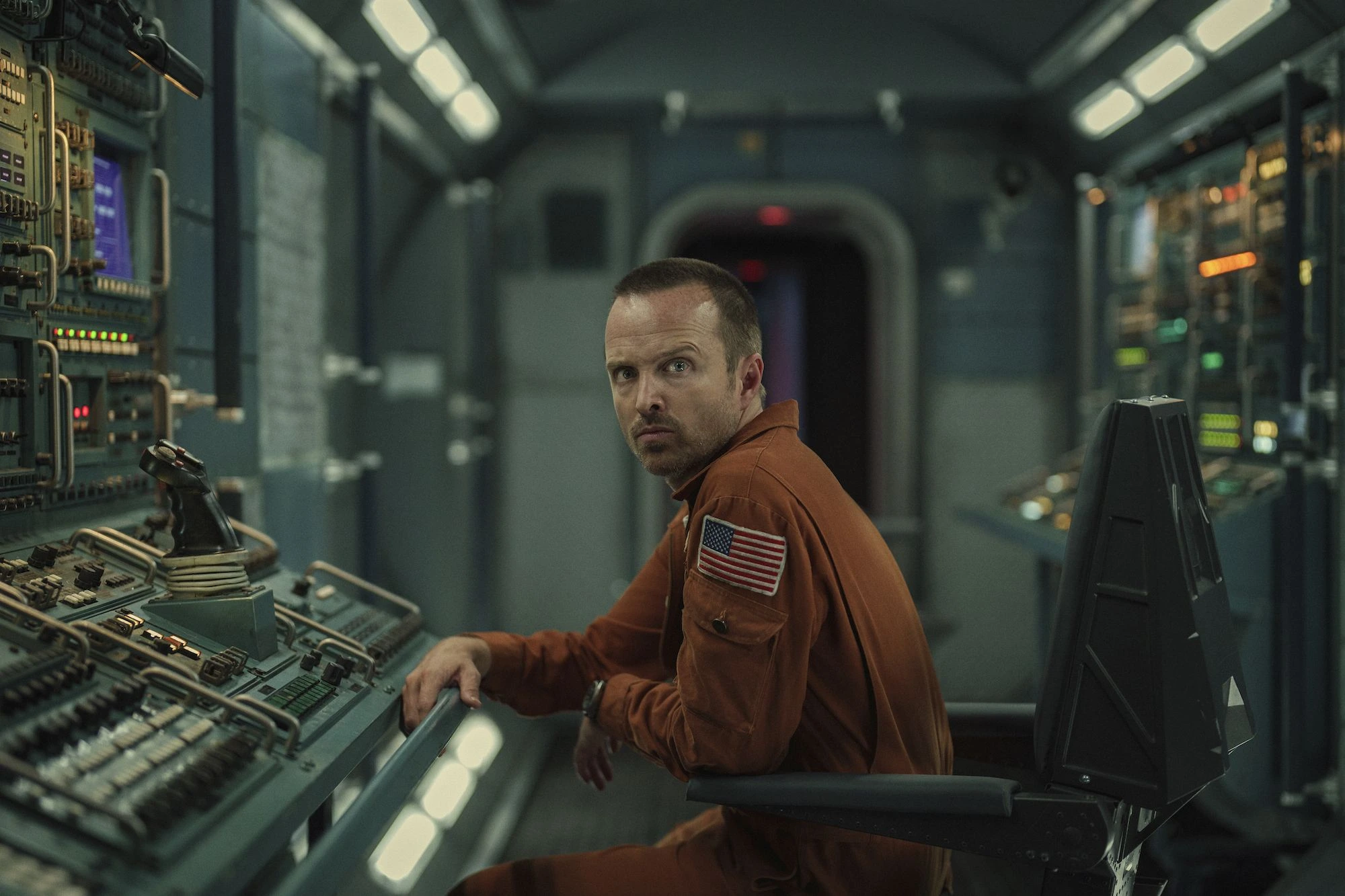 Aaron Paul (actor) vestido de astronauta en una sala llena de botones y palancas