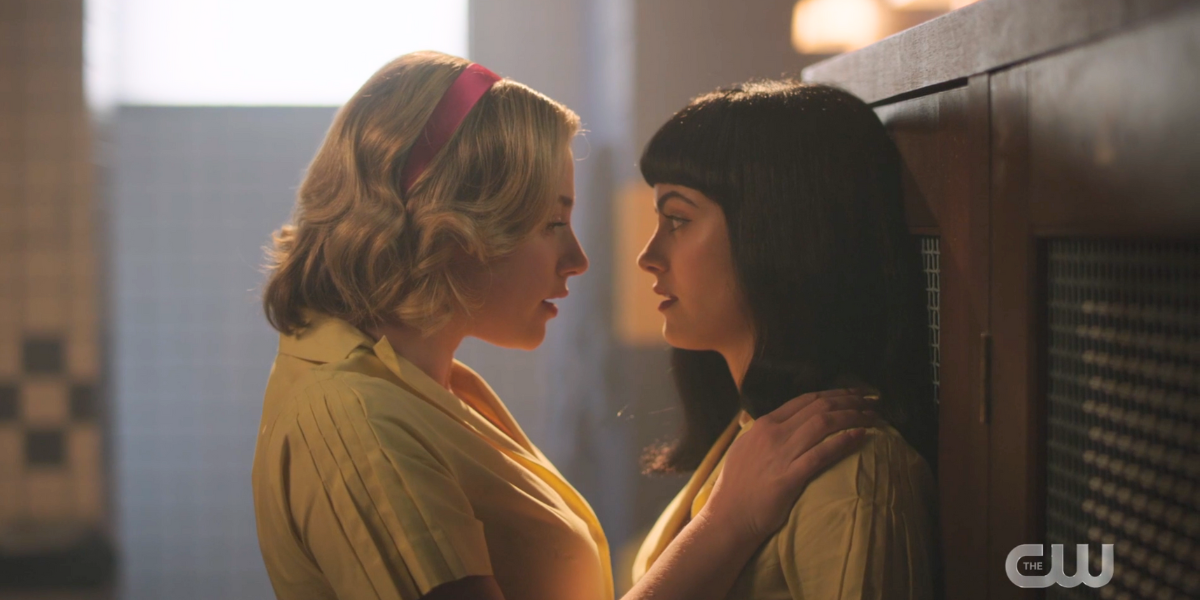 Betty Cooper mirando a los ojos a Veronica Lodge, a punto de besarla