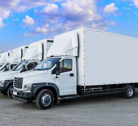Some trucks are parked in a parking lot next to a logistics warehouse by the river. Severa