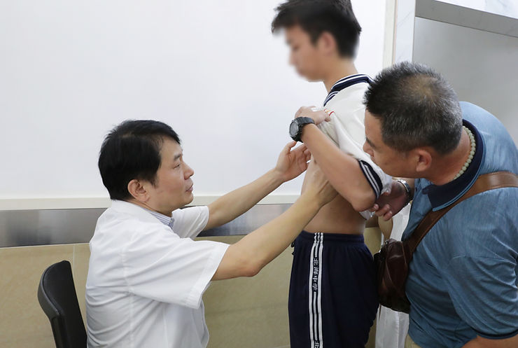 Dr. Wenlin Wang is examining the patient's chest wall.