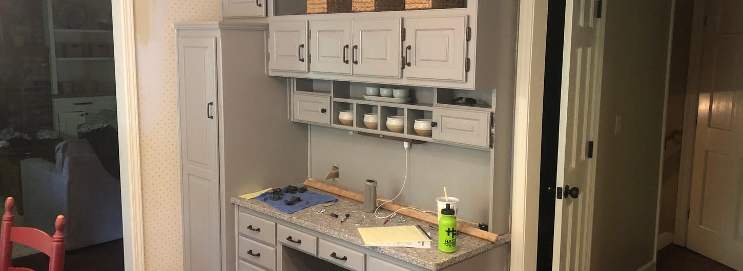 After kitchen cabinet painting, beautifully updated light gray painted built-in hutch, cabinets, drawers, and desk area with new countertop in this fresh home remodeling transformation by (BDS) Brian's Drywall Services in Leawood, KS