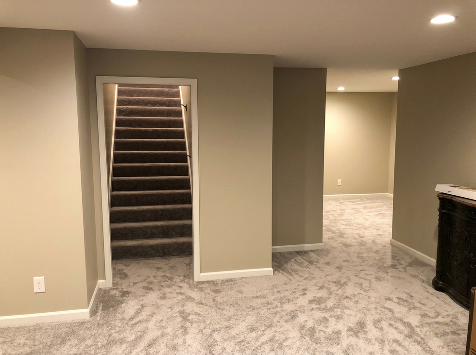 Professional basement remodel and interior painting by Brian’s Drywall Services (BDS) in Overland Park, KS – smooth painted gray walls, white baseboards and door casings, carpeted floors, and carpeted staircase after full drywall hanging, finishing, and painting throughout the Kansas City metro area