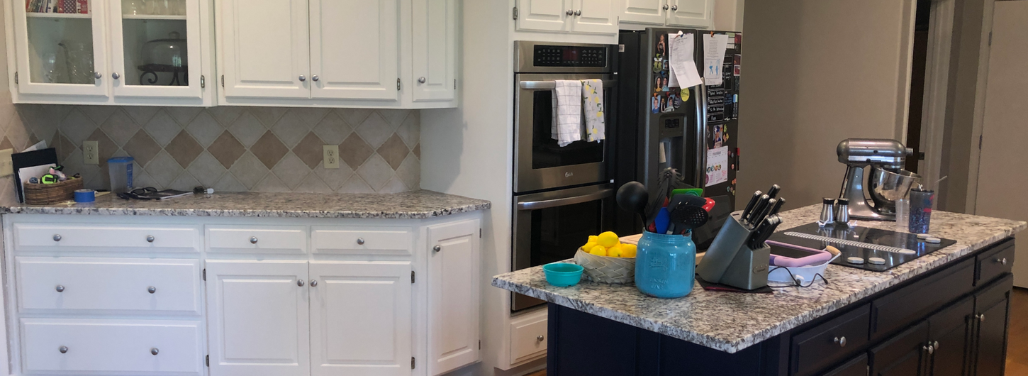 Professional kitchen remodeling project showcasing expert kitchen cabinet painting with smooth white painted upper and lower perimeter cabinets, a contrasting dark navy blue painted kitchen island with granite countertops, and clean drywall finishing on the surrounding walls, completed by (BDS) Brian's Drywall Services in Raymore, MO.