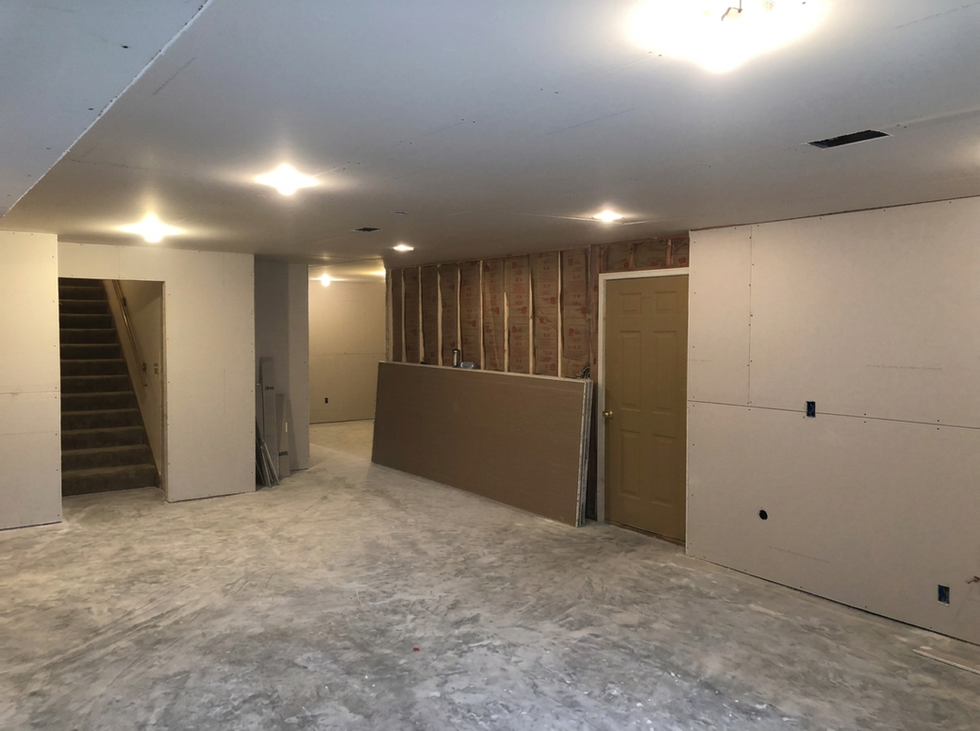 Professional drywall hanging by Brian’s Drywall Services (BDS) in an Overland Park basement remodel – smooth drywall panels on walls and ceiling, leftover sheets stacked, and open framing with insulation visible, serving the Kansas City metro area