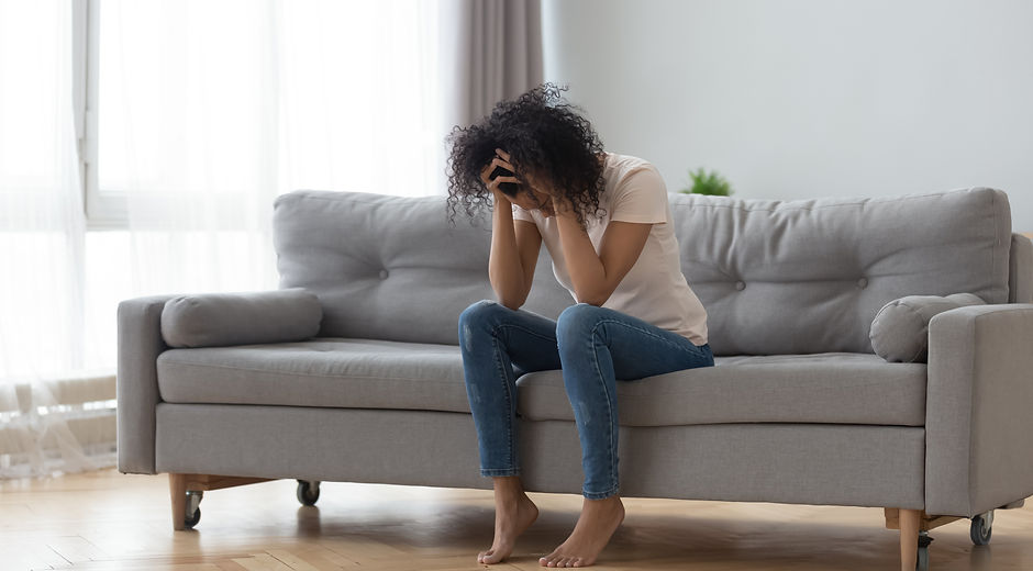 Stressed African American Woman feeling overwhelming anxiety sitting on couch 