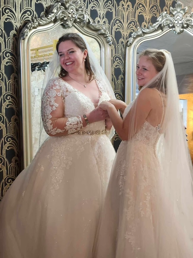 Meg (R, plus-sized) shops for a wedding dress with her best friend, Elizabeth (L, straight-sized) at Down the Aisle