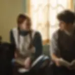 Two young people sit by a window, one with a notebook, the other with a book. Sunlit curtains create a warm, contemplative mood.