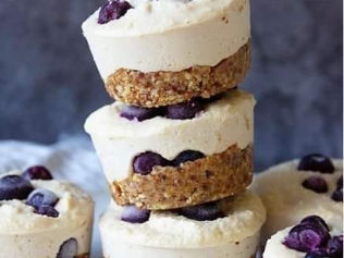 Three stacked mini cheesecakes with a biscuit crust, topped with blueberries. Set against a dark background, creating a delicious and inviting mood.