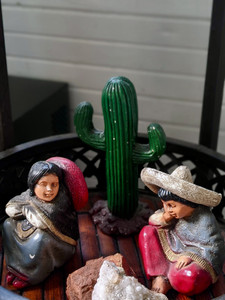 Mexican figurines sitting next to a cactus