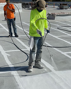 MAN SPRAYING ROOF COATING ON ASPHALT ROOF