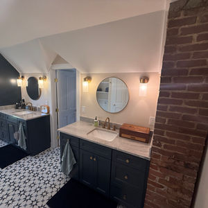 Bathroom remodel with custom tile installation and dark green vanities.