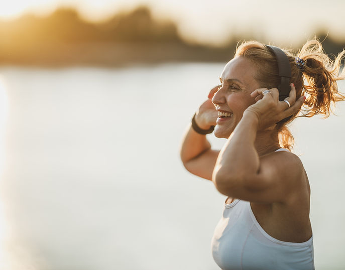 A middle age sportswoman listening to music and preparing to working out near to river, in