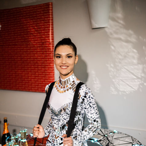 Showgirl performer wearing a walking table costume and serving food and alcoholic beverages to guests at an event.