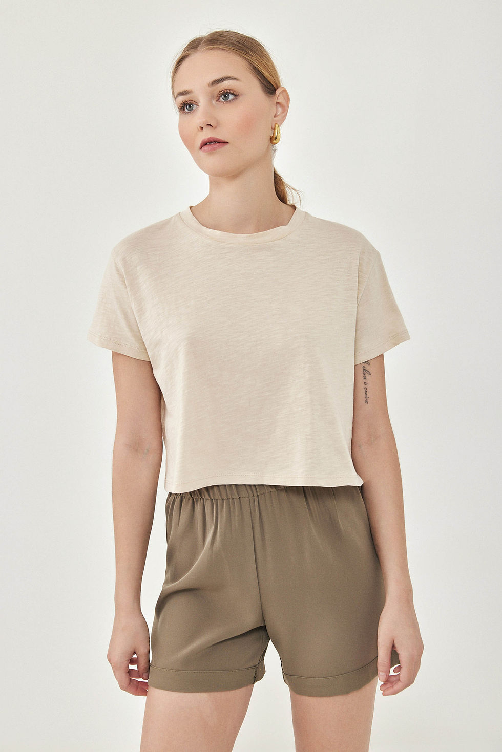 Thumbnail: Woman in cream cropped t-shirt and olive green shorts