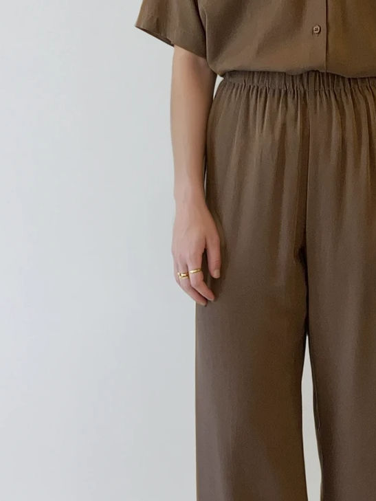 Woman's hand with rings, brown wide-leg pants