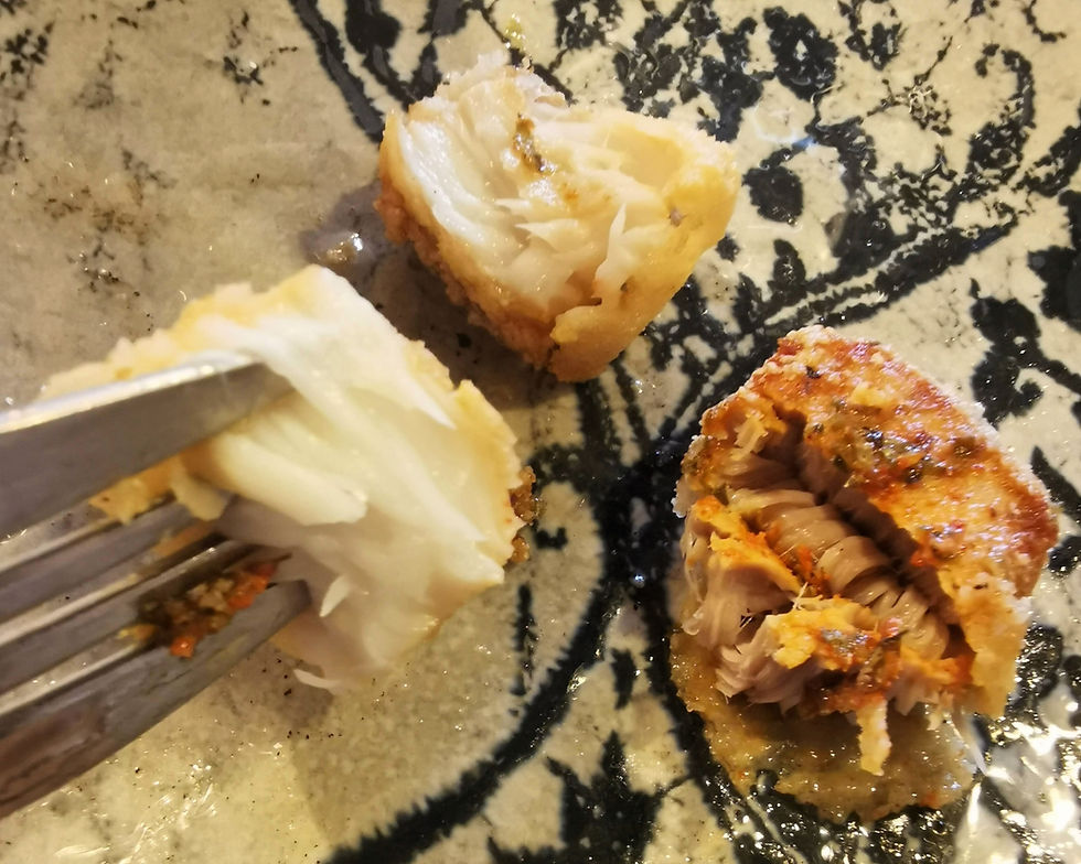 small dice-shaped bites of fried cod-fish on a fork and on the plate..