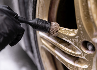 Car wash worker cleaning sports car wheel with a special brush.jpg