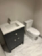 Remodeled bathroom with dark vanity, white sink, and toilet.