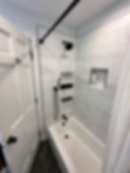 Modern bathroom with white tiled shower, black fixtures