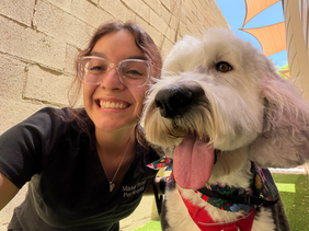 Smiling employee with a fluffy white dog at work.
