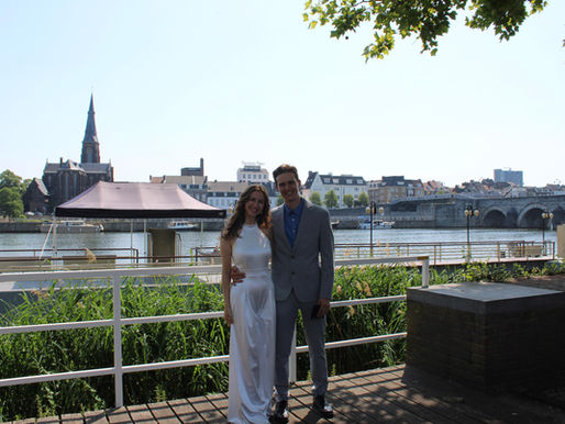 A woman and a man standing in front of the Maas River.
