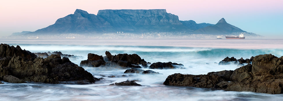 Tafelberg im Sonnenaufgang von Milnerton aus mit weißen Wellen im Dunst