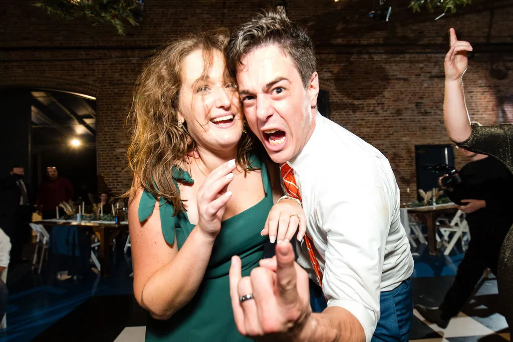 woman in green dress and man in orange tie facing camera and posing