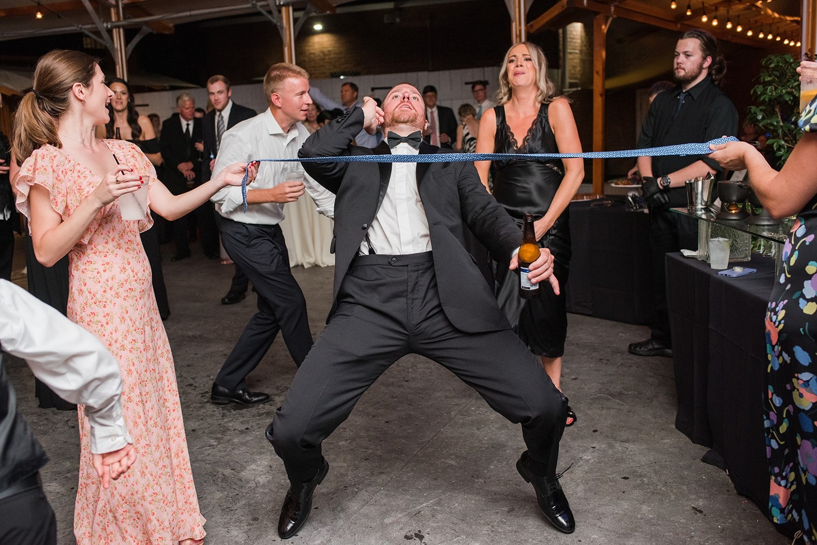 guy doing limbo under a tie at wedding