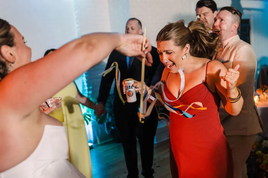 woman in red dress dancing with bride and other guests