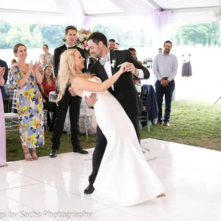 groom dipping bride during their first dance as guests watch