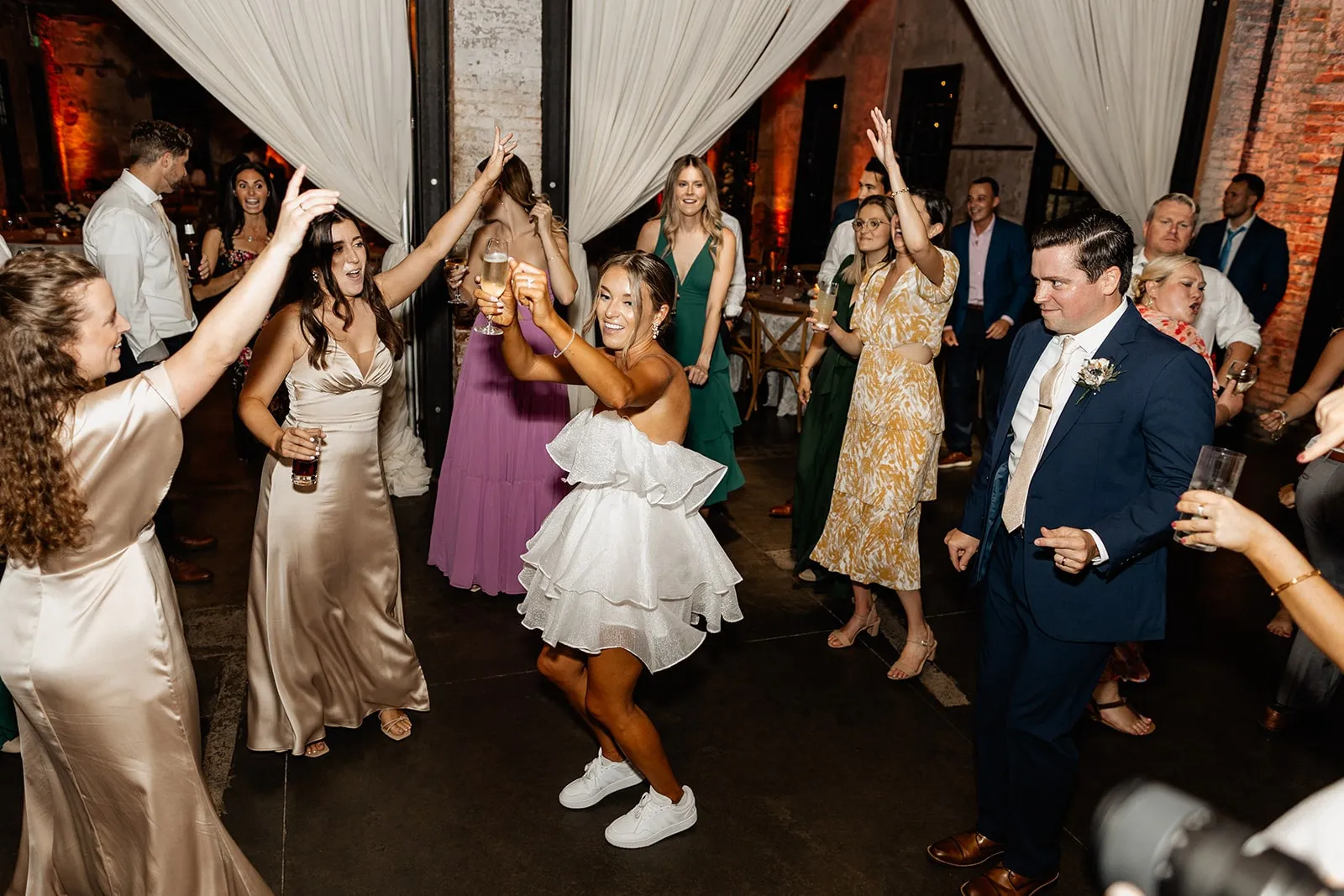 bride with white party dress dancing with guests