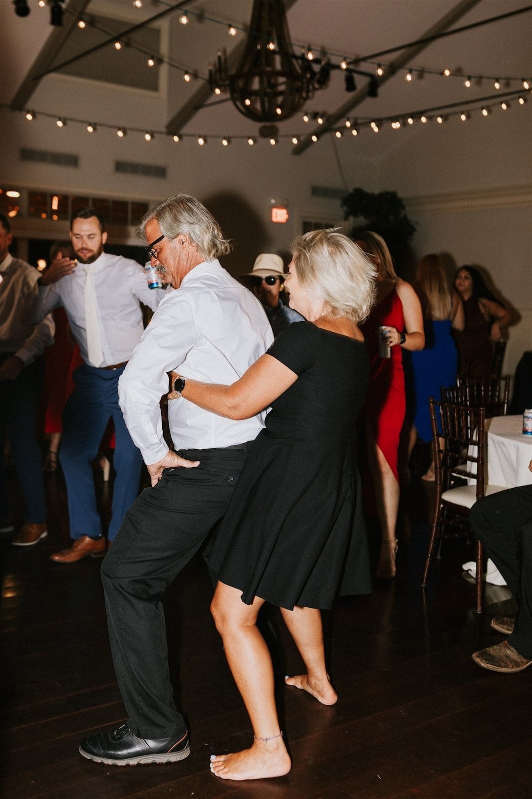 older couple dancing with guy in front and woman in black dress behind him