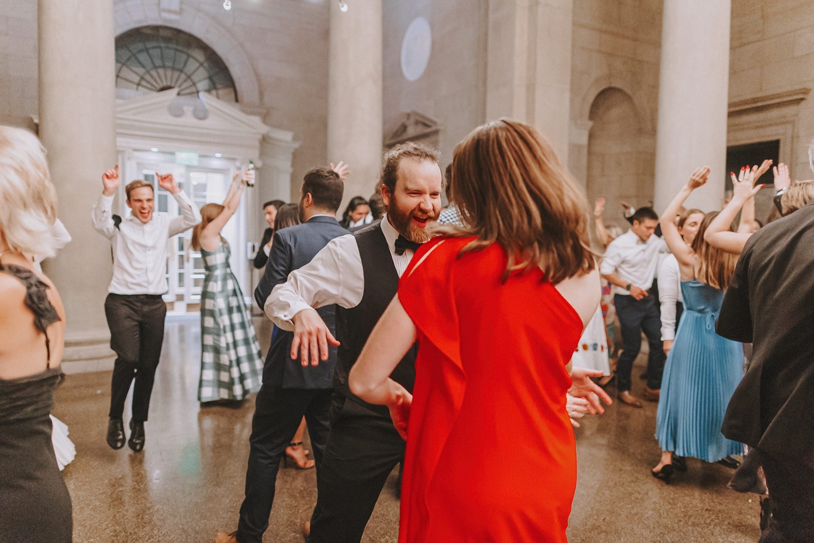 woman in red dress and guy in tux dancing at wedding