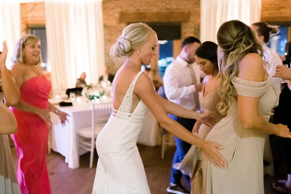 bride dancing with her hands on bridesmaid's butt in front of her