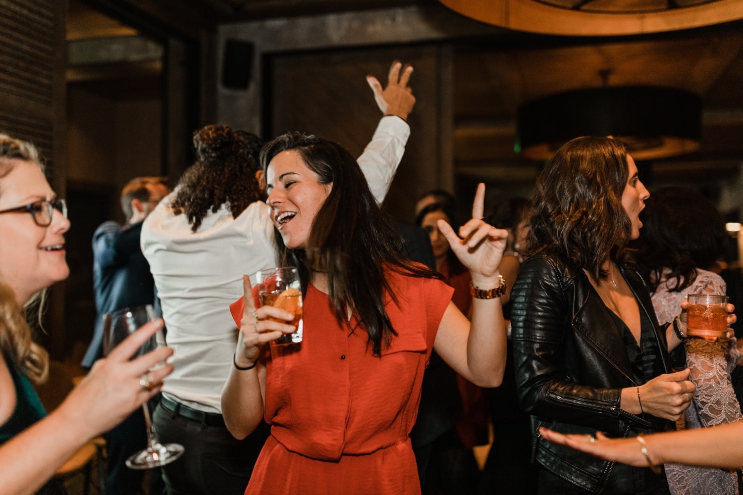 woman in orange dress dancing with drink in one hand