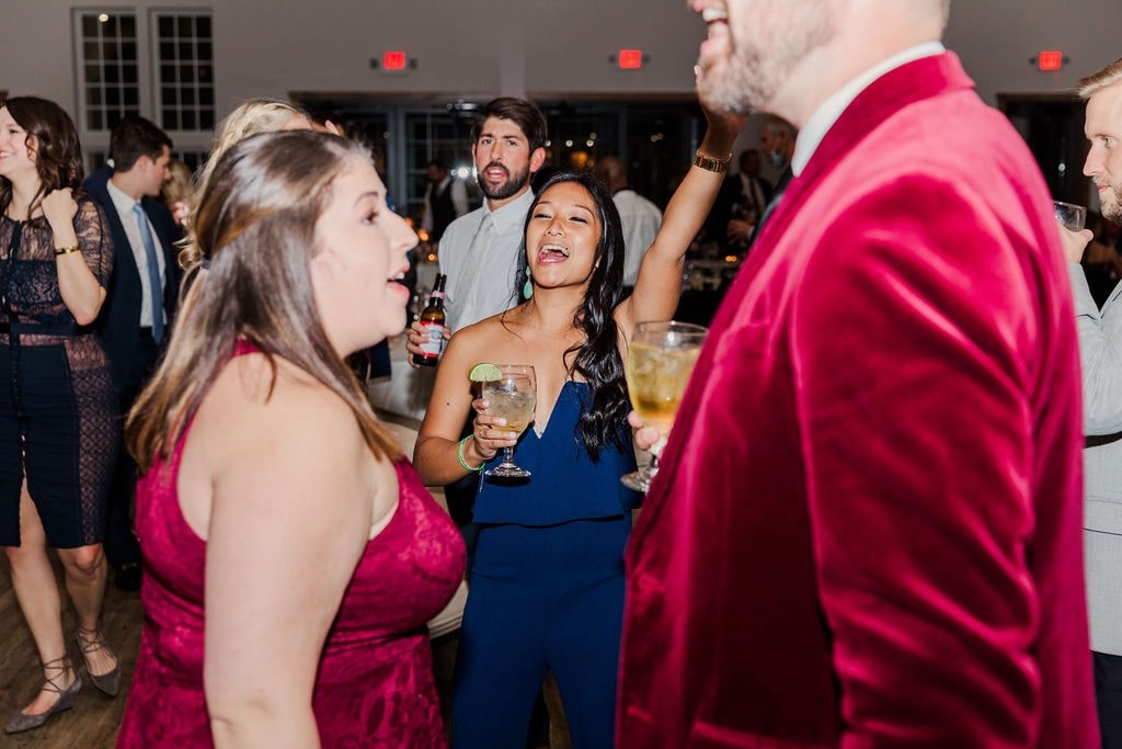 woman in blue dress dancing with hand up with woman and man in red