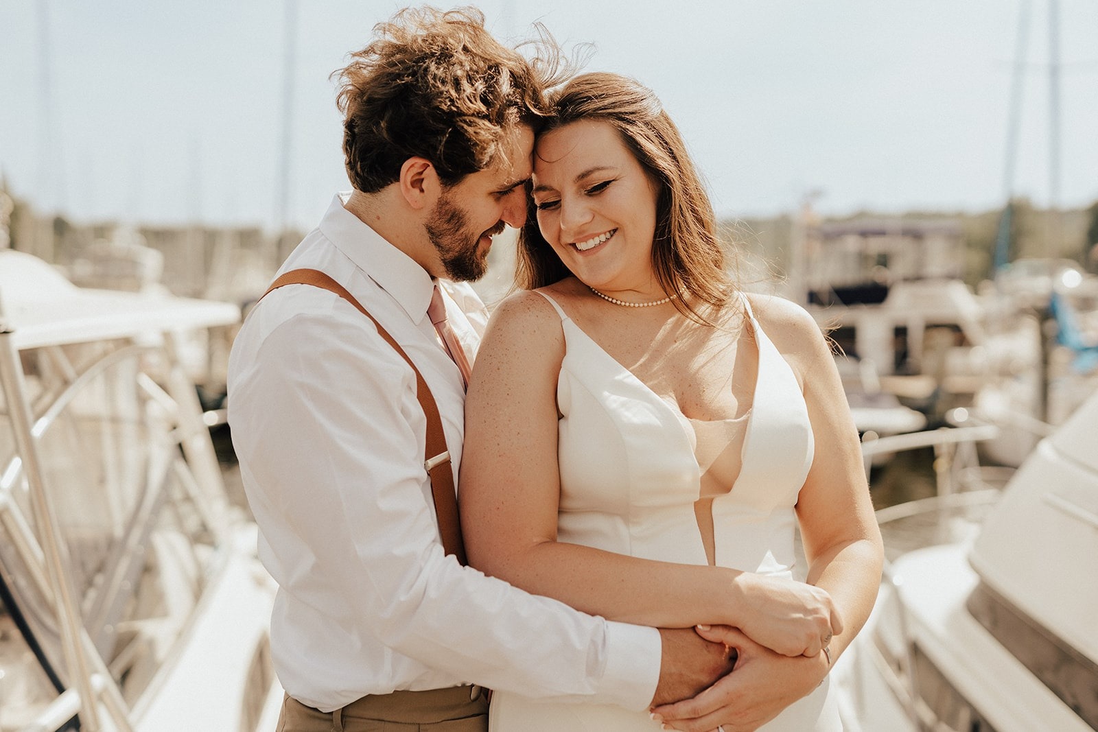 bride and groom pose by boats