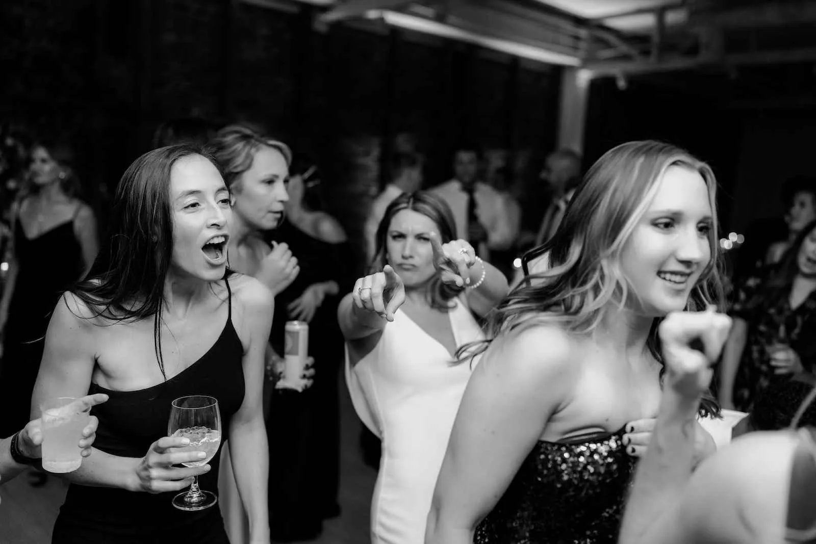 women dancing while bride points with both hands at the camera