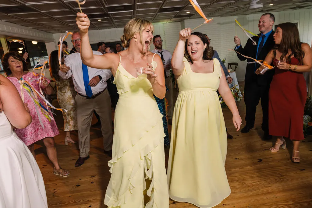 bridesmaids in yellow dresses dancing and waving ribbons on sticks around