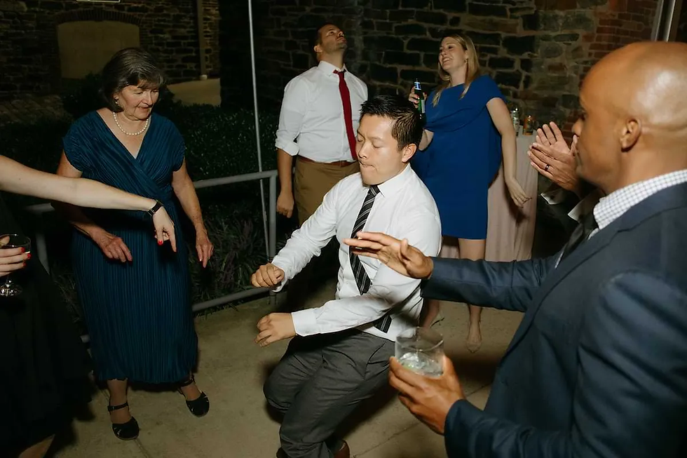man wearing a tie is dancing in center of group on a patio