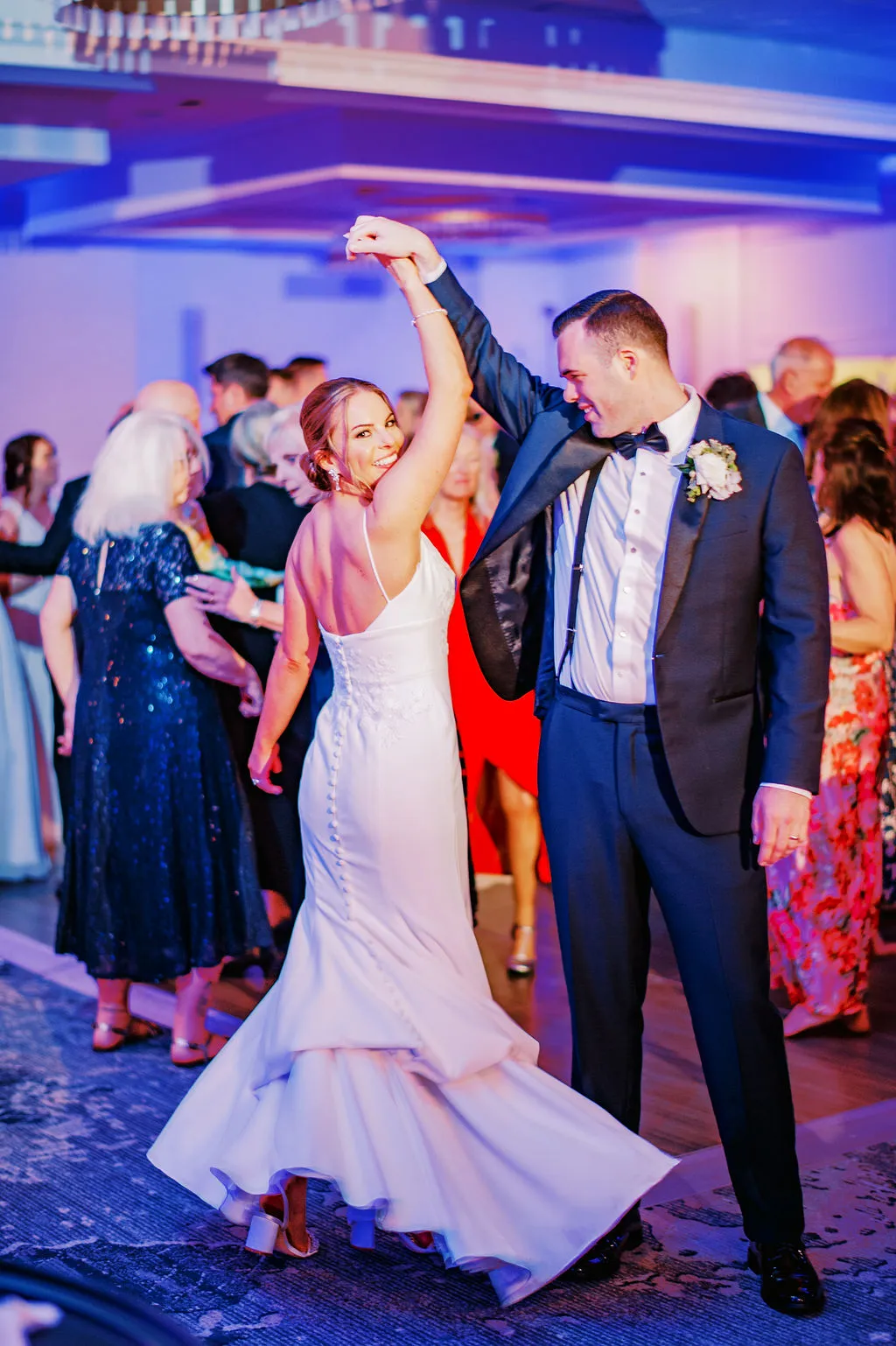 groom spinning bride while dancing around guests