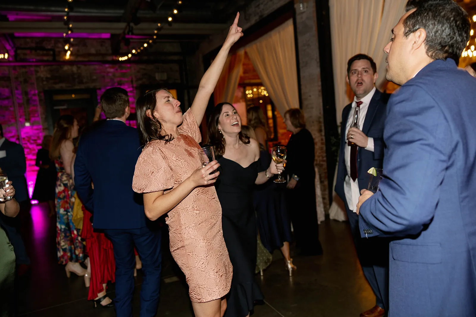 woman in peach-colored dress dancing with hand pointing up